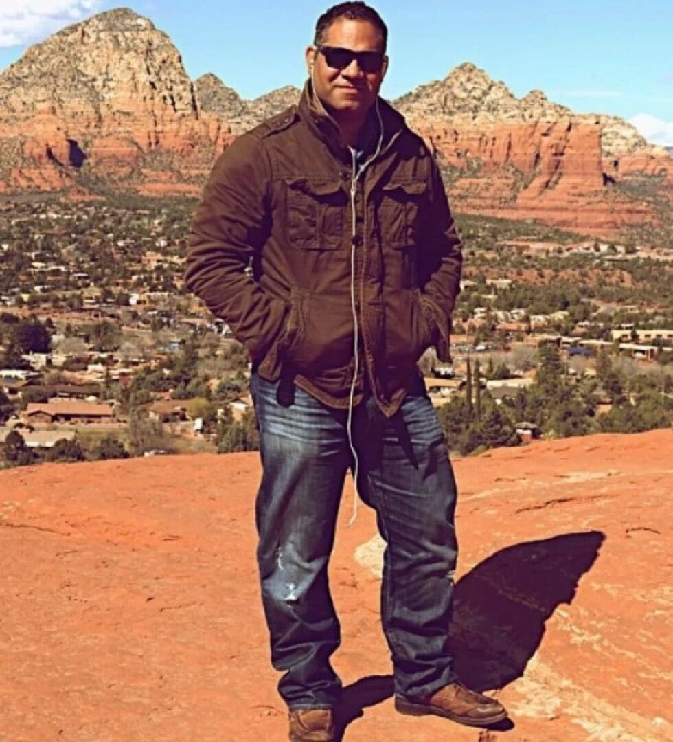 A man standing on top of a hill in front of some mountains.